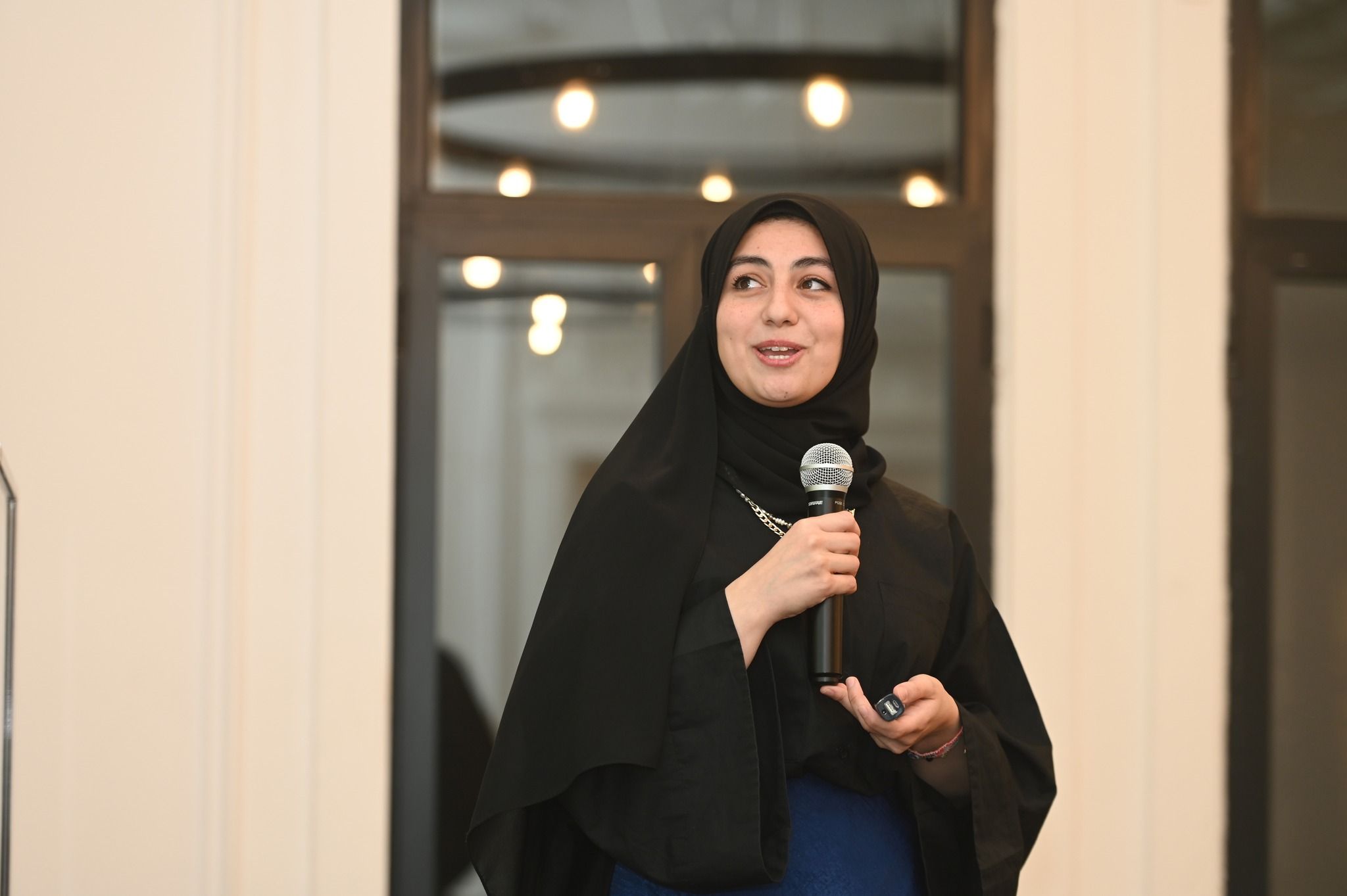 متحدثة تمسك الميكروفون وتروي قصتها أمام المشاركين